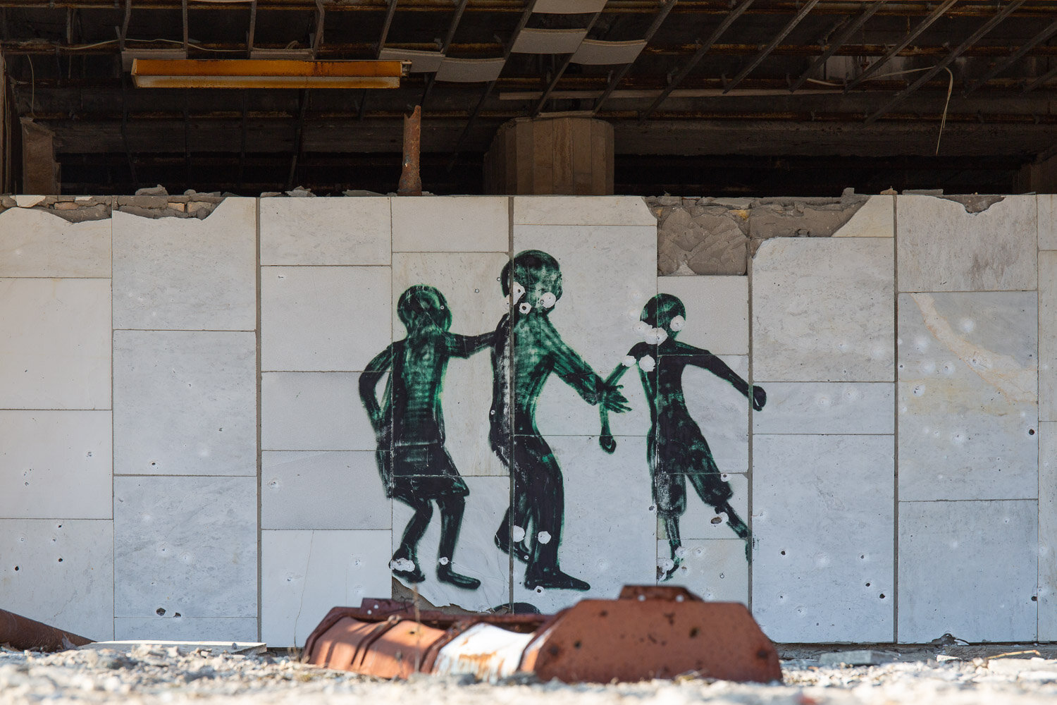 Street art of three figures jumping over a barrel